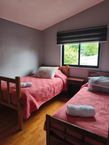 a bedroom with two beds and a window at Ventisqueros Coyhaique in Coihaique