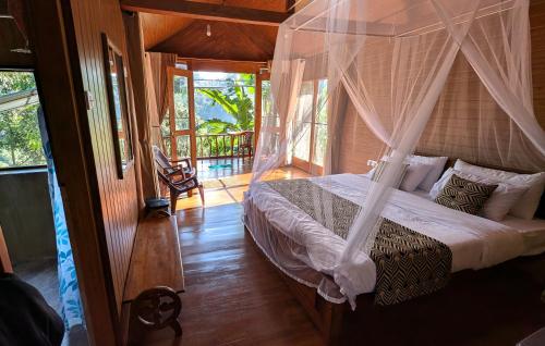 a bedroom with a bed with a mosquito net at Ella Antara Green Wood Cottage in Ella