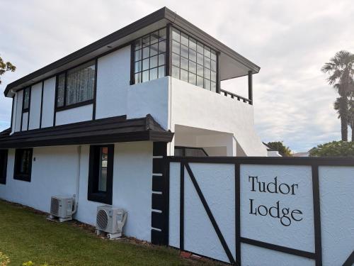 a white house with a sign that reads idiot lodge at Tudor Lodge Motel in Nelson