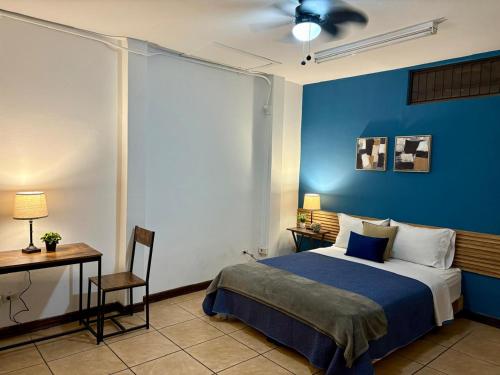a bedroom with a blue wall with a bed and a desk at Luca in San José