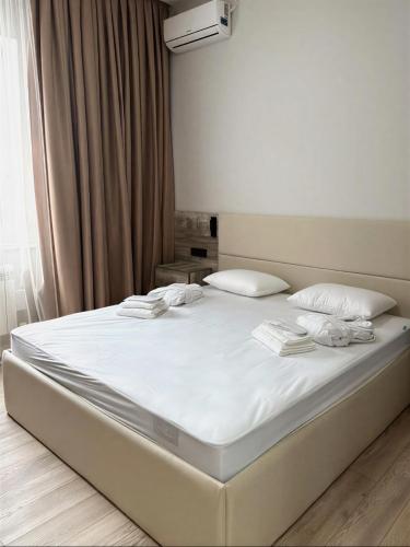 a bed in a bedroom with white sheets and pillows at Small Cozy Spa Hotel in Aktobe