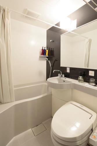 a white bathroom with a toilet and a sink at Candeo Hotels Kikuyo Kumamoto Airport in Kikuyo