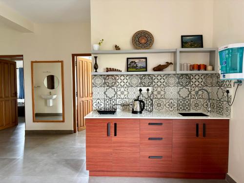 a kitchen with wooden cabinets and a tile wall at Sudama Cityscapes in Cochin