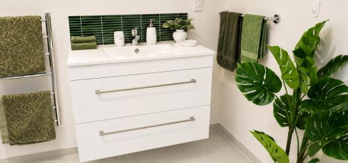 a bathroom with a white sink and a plant at Hill Top Hideaway - Self Contained Guest Suite with Private Spa in Pukerua Bay