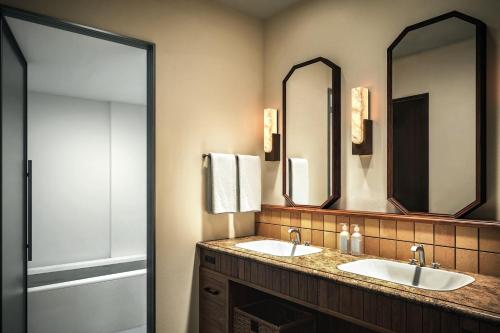 a bathroom with two sinks and two mirrors at The Alps Hotel Hakuba in Otari