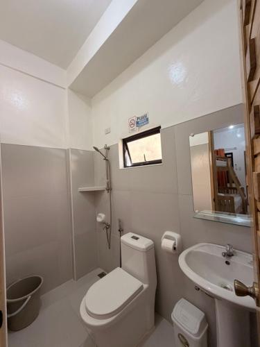 a white bathroom with a toilet and a sink at NOGS Homestay, near Magpupungko, Siargao Island Surfings Spots in Pilar