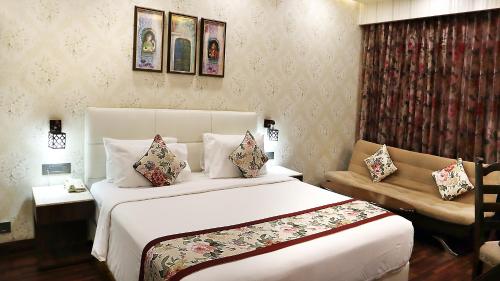 a bedroom with a large white bed and a couch at Hotel Grand Maple in Jaipur