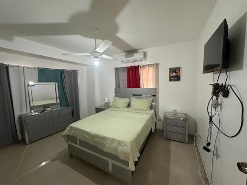 a bedroom with a bed and a flat screen tv at Central Suites Jaraba in Jarabacoa