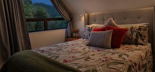 a bedroom with a bed with pillows and a window at Hill Top Hideaway - Self Contained Guest Suite with Private Spa in Pukerua Bay