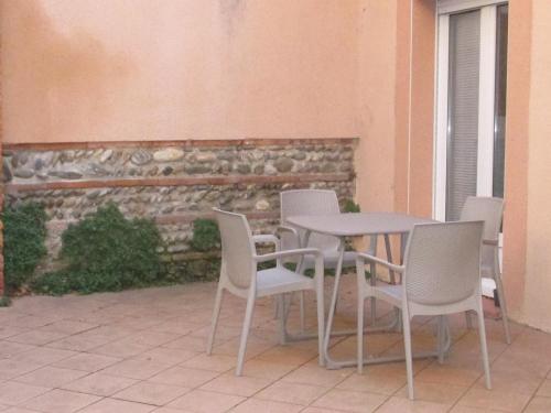 d'une terrasse avec une table, des chaises et un mur. dans l'établissement Résidence le Pastel François Verdier, à Toulouse