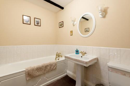 a bathroom with a sink and a tub and a mirror at Bramble Cottage in Wooler
