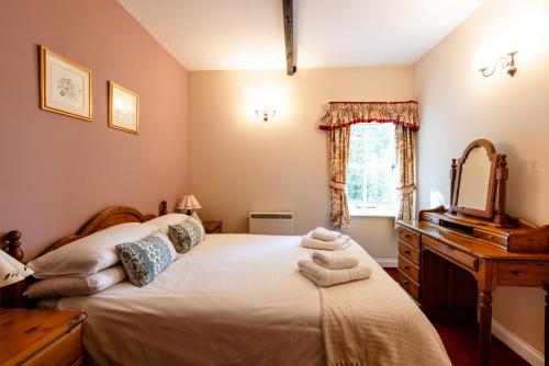 a bedroom with a bed and a mirror and a window at Fern Cottage in Wooler