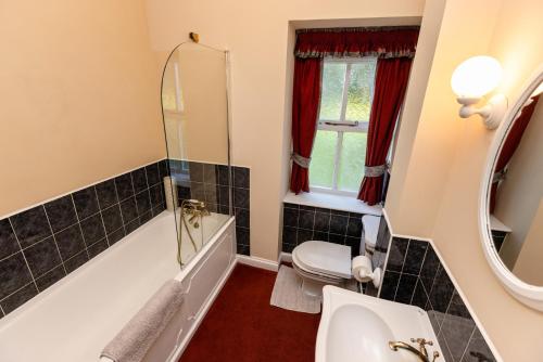 a bathroom with a tub and a toilet and a sink at Fern Cottage in Wooler