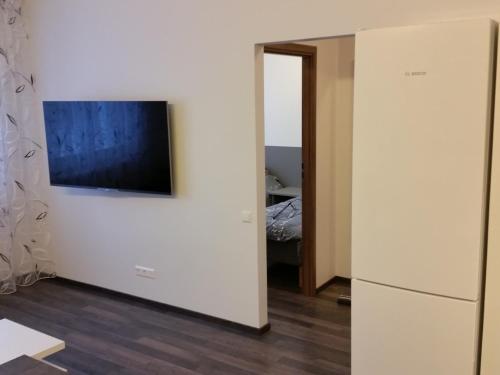 Habitación con pared blanca, TV y nevera. en Tehvandi Ski Apartment en Otepää
