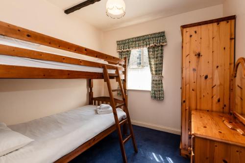 a bedroom with two bunk beds and a window at Blueberry Cottage in Wooler