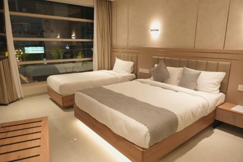 zwei Betten in einem Hotelzimmer mit Fenster in der Unterkunft Hotel D' Paris in Kozhikode