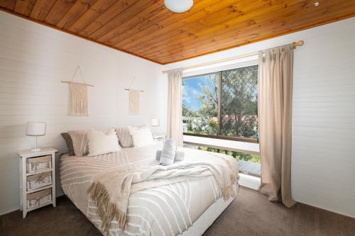 a bedroom with a bed and a large window at Drifters @ Callala Beach in Callala Beach