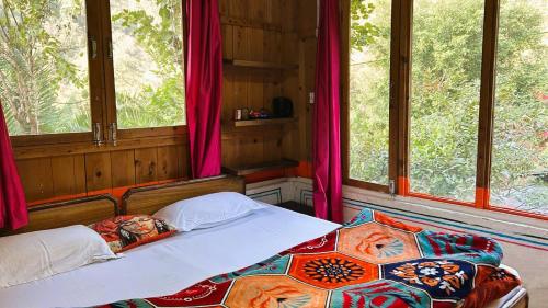 ein Schlafzimmer mit zwei Betten in einem Zimmer mit Fenstern in der Unterkunft Rishikesh Valley in Rishikesh