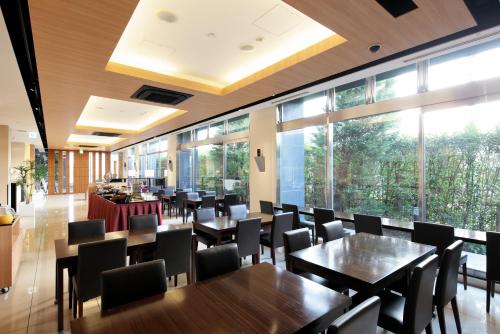 a restaurant with tables and chairs and large windows at Candeo Hotels Kikuyo Kumamoto Airport in Kikuyo