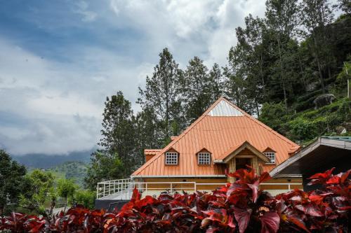 an orange roofed house with red plants in front of it at The Door to Nirvana Backpackers Hostel Kotagiri in Kotagiri