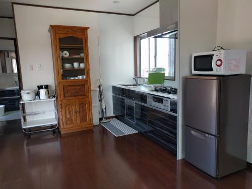 a kitchen with a stainless steel refrigerator and a microwave at Unbi Stay -SEVEN Hotels and Resorts- in Nakijin