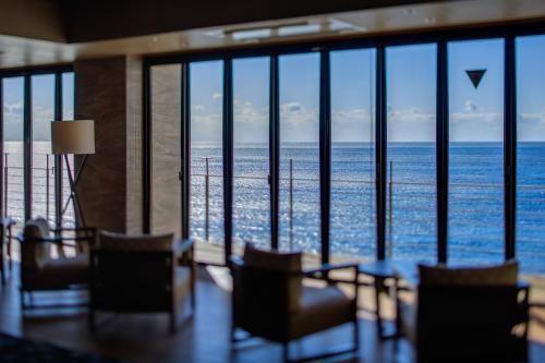 a room with chairs and a view of the ocean at Inatori Ginsuiso in Higashiizu