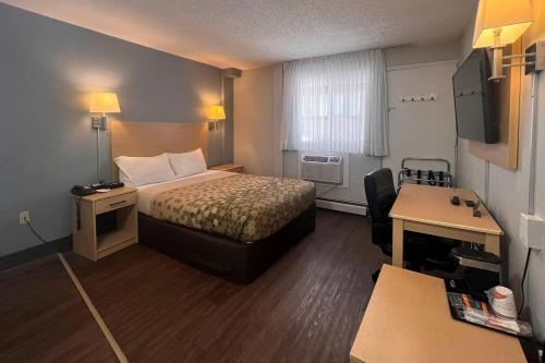 a small hotel room with a bed and a desk at Econo Lodge Motel Village in Calgary