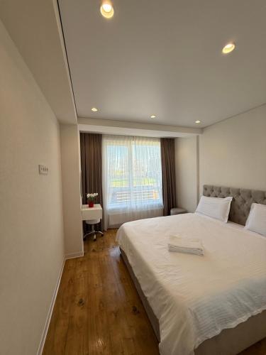 a bedroom with a large white bed and a window at Apartamentul white Arena in Chişinău