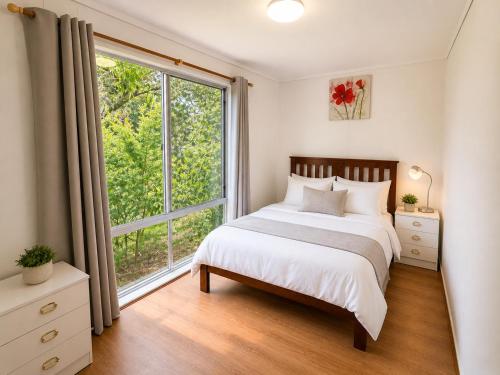 a bedroom with a bed and a large window at Apollo bay Holiday House in Apollo Bay