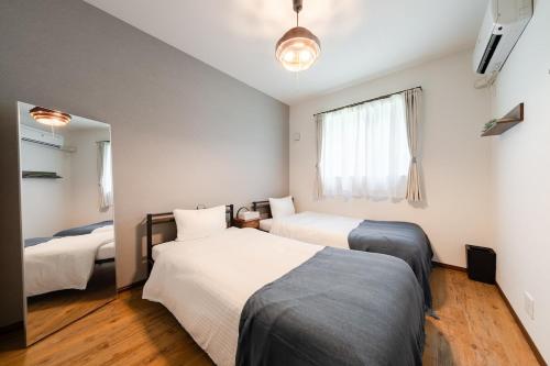 a bedroom with two beds and a window at Value residence Kugai 3A in Miyako-jima