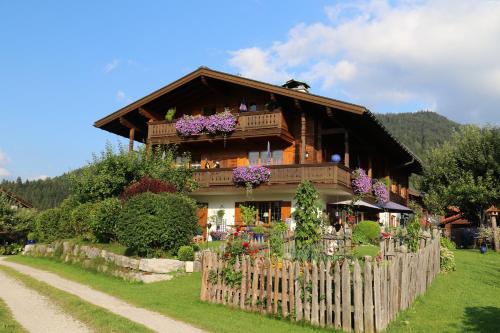 a large wooden house with flowers in front of it at Gästehaus Schönfeld in Reit im Winkl