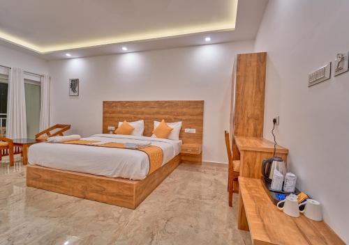 a bedroom with a large bed and a desk at Ice Mist Pool Resort Munnar by VOYE HOMES in Munnar