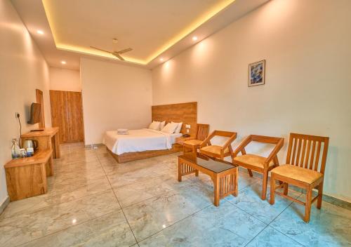 a hotel room with a bed and a table and chairs at Ice Mist Pool Resort Munnar by VOYE HOMES in Munnar