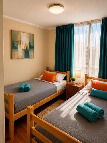 a bedroom with two beds with blue pillows at Departamentos Amoblados Torre Tagle in Santiago