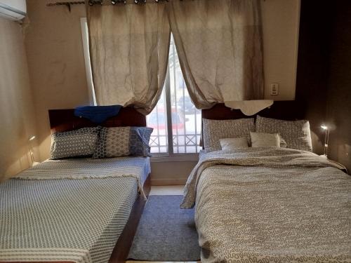 a bedroom with two beds and a window at Madinaty Summer cottage in Cairo