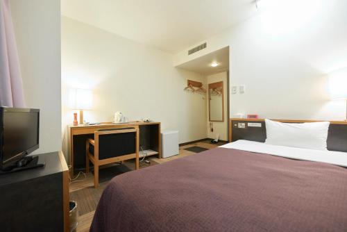 a bedroom with a bed and a desk and a tv at Select inn Iwaki Ekimae in Iwaki