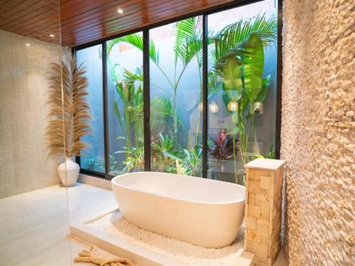 a bath tub in a bathroom with a large window at Harbie Villa in Seminyak