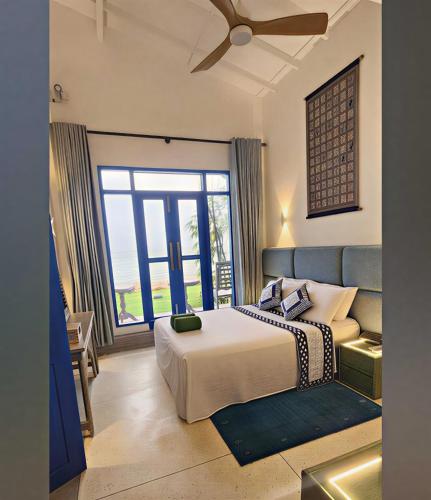 a bedroom with a bed and a large window at Refuge Boutique Villa in Hikkaduwa