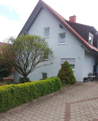 a white house with a tree and a brick driveway at Ferienwohnung Kemmerth in Ebermannstadt