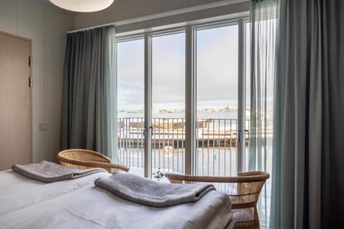 a bedroom with a bed and chairs and a large window at Gullmarsstrand Hotell & Konferens in Fiskebäckskil