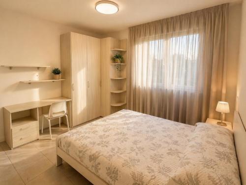 a bedroom with a bed and a desk and a window at Residence Antares - Agenzia Cocal in Caorle