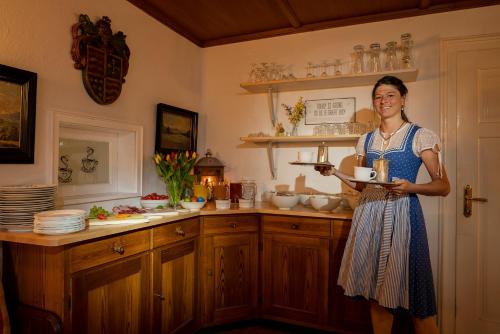 a woman is holding a plate in a kitchen at Gästehaus Heiß in Lenggries