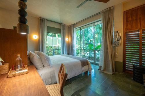 a bedroom with a bed and a table and windows at Querida Casa - Mérida Centro in Mérida