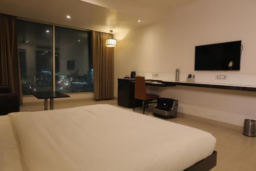 a hotel room with a bed and a desk and a television at The Ashoka Hotel in Howrah