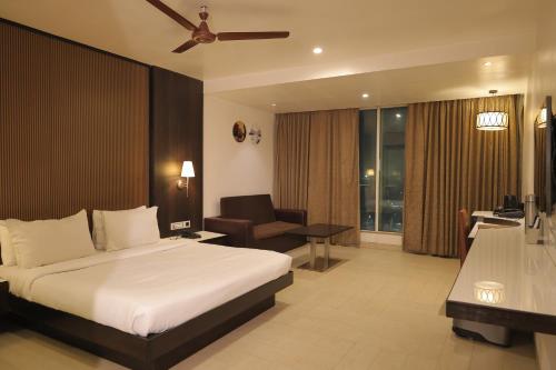 a bedroom with a bed and a chair and a desk at The Ashoka Hotel in Howrah