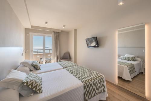a hotel room with two beds and a mirror at Les Dunes Comodoro in Benidorm