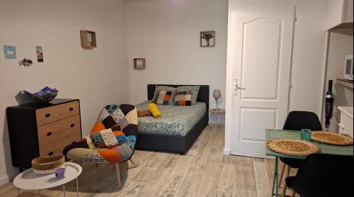 a living room with a bed and a table at studio cosy meublé, terrasse et patio pour vélo in Rochefort
