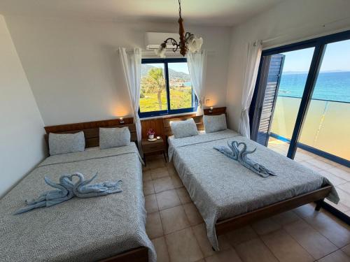two beds in a room with a view of the ocean at Kanalli Apartments in Pomos
