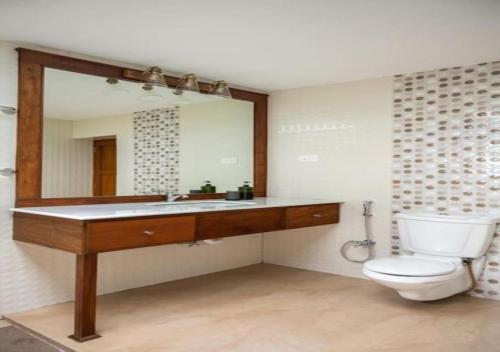 a bathroom with a toilet and a large mirror at Villa Mariam in Cheruvalli