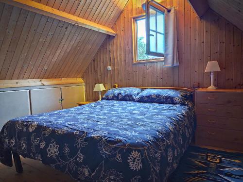 a bedroom with a bed in a wooden room at La maison bleue in Saint-André-dʼHébertot